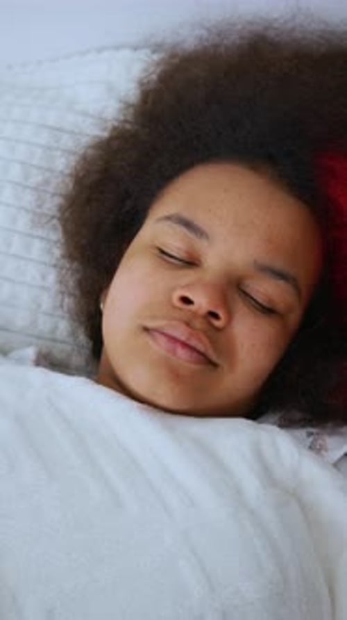 Young Person Peacefully Sleeping in a Cozy Bed with Soft Blankets in a Welllit Room