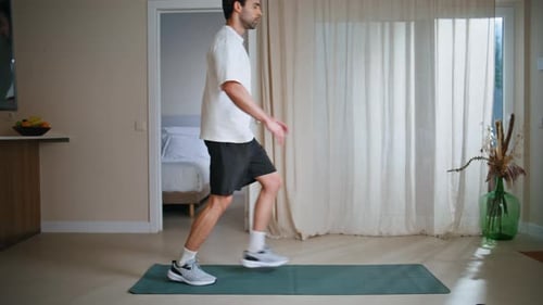 Young Man Performing Lunges on a Yoga Mat