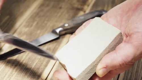 Sharpening a rusty knife on a grinding machine, sparks are flying, close-up.