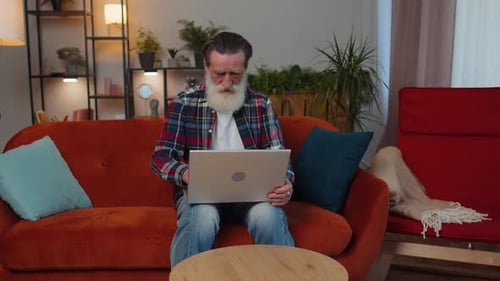 Senior Man Works on Laptop in Living Room