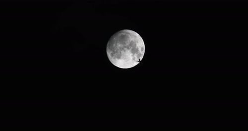 Airplane passing full moon