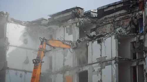 Excavator Demolishing Building in Urban Area