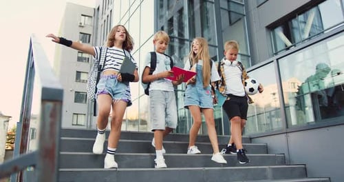 Group of four young attractive caucasian students walking together down the stairs in college campus