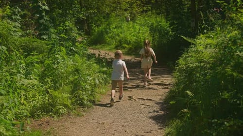 Girl and Boy Run Along Ground Forest Path on Summer Day