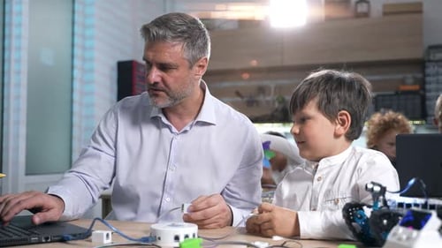 Adult Helping Child With Computer Coding Project