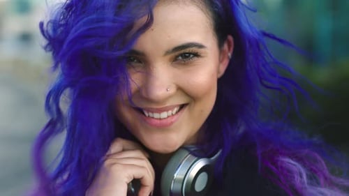 Portrait of an edgy and trendy woman streaming music, listening on headphones