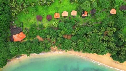 Vista aérea do resort com bangalôs na praia e no mar azul-turquesa.
África