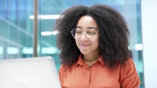 Confident african american businesswoman talking on video call using a laptop sitting in office.