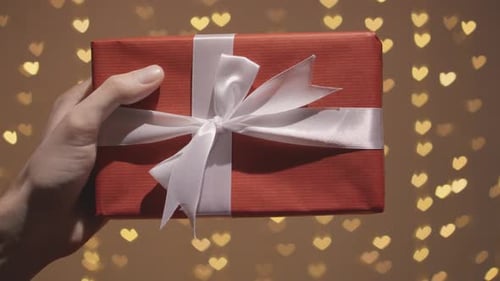 Hand Holding Gift with Heart Light Background