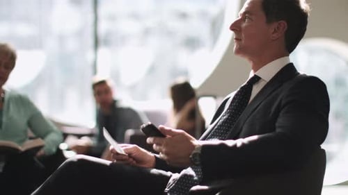 Business man waiting in airport lounge on mobile phone