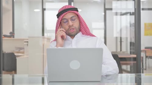 Man Works on Laptop While on Phone