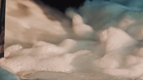 Close up of thick white foam swirling in moving water, creating a soft textured visual