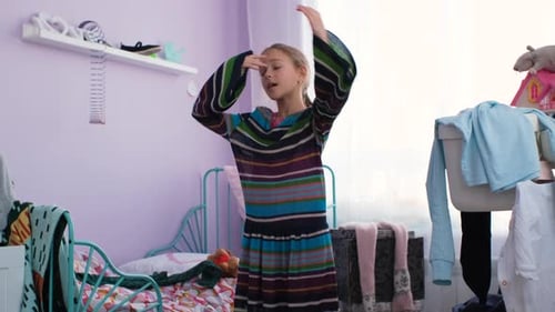 Menina experimentando um vestido grande enquanto está sozinha em casa