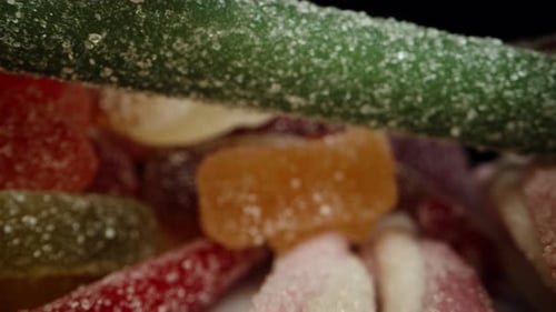 A mix of gummy candies in different colors and flavors, dusted with sugar. The camera is inside this