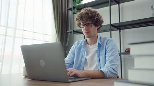 Kaukasischer junger Geschäftsmann, der von zu Hause aus am Computer tippt.