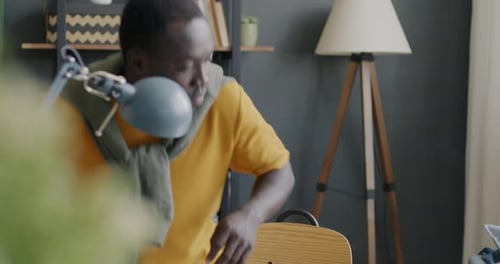 African American Man Freelancer Sitting at Desk in Home Office and Working with Laptop Computer