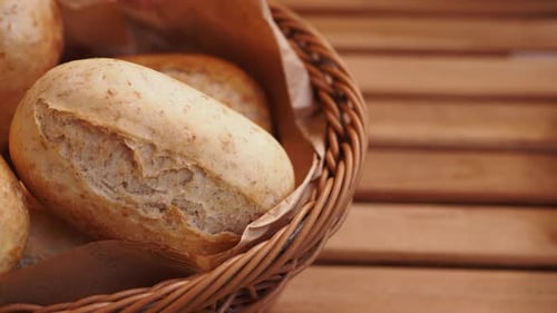 Freshly Baked Rolls in a Woven Basket on a Wooden Table