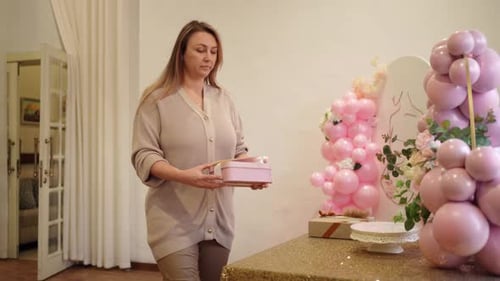 Woman Sets Birthday Gift at Party Table