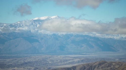 Ein faszinierender Blick auf schneebedeckte Berggipfel mit sich langsam bewegenden Wolken, die ein atemberaubendes n