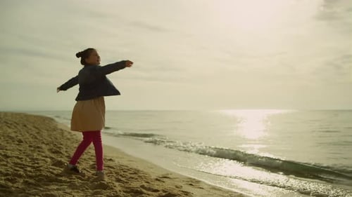 Little Child Dancing Beach at Sunset Sea. Happy Girl Playing Alone Outdoors