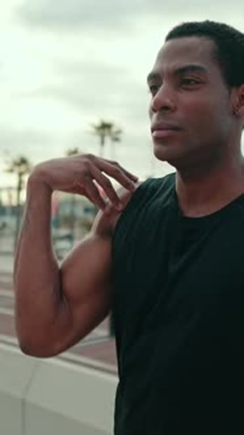 Vertical video, Fit African American Man Stretches at Harbor