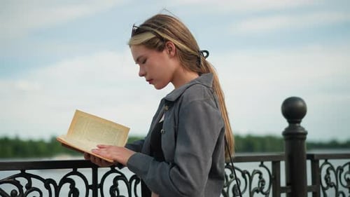 Young Woman Reading Book Outside On Sunny Day