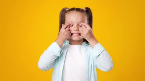Happy Child Making Funny Faces Against Bright Yellow Background