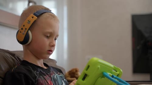 A Caucasian boy watches a video lesson while studying at an online school.