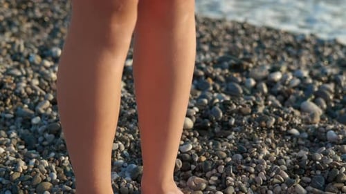 A Child's Bare Feet on a Pebble Beach