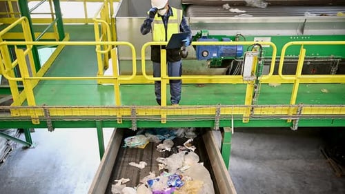 Employee Inspecting Plastic Waste on Conveyor Belt