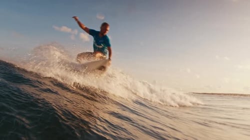 Surfer Riding Wave at Sunrise