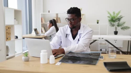Doctor Analyzing Xray Results at Desk in Medical Office