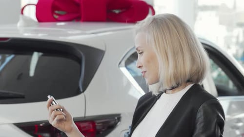 Charming Woman Smiling Brightly While Holding Car Keys in a Dealership