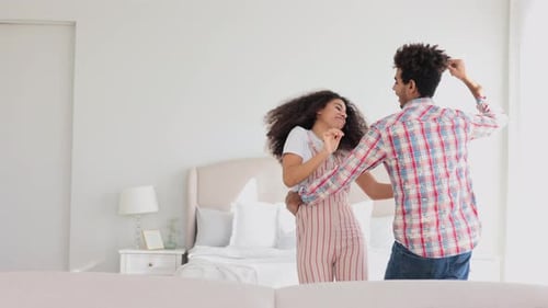 Happy Couple Dancing Together in Bright Bedroom