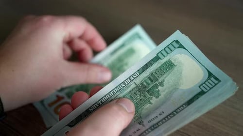 Close-up view of a young adult man counting money.