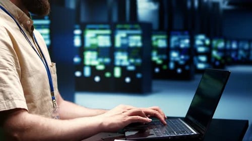 Adult Typing on Laptop in Modern Server Room