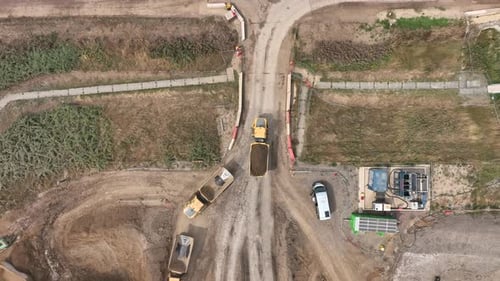 Construction Site Aerial View with Dump Trucks Moving Dirt