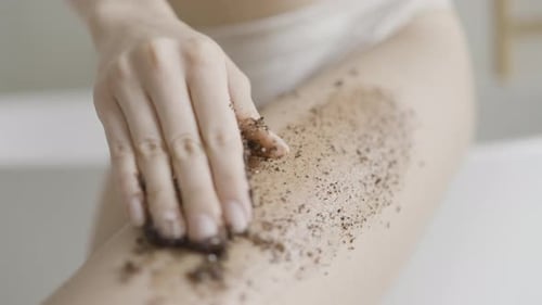 Woman Applying Coffee Scrub on Leg for Skin Care