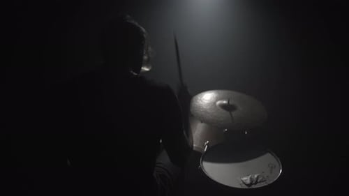 Silhouette eines Mannes, der im Dunkeln Schlagzeug spielt