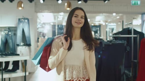Happy young brunette girl is walking though a clothing store.