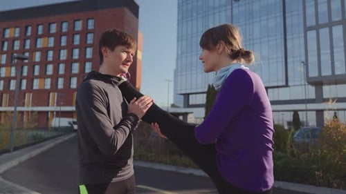 Fit Couple Stretching Outdoors Helping Each Other During a Workout in the City