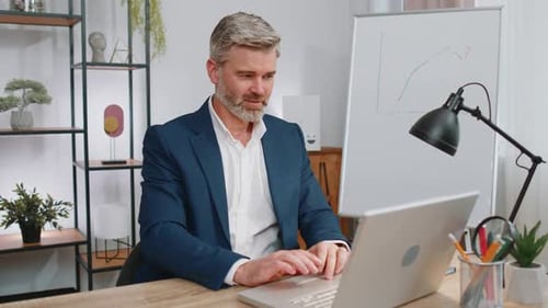 Mature Business Man Freelancer at Office Start Working on Laptop Computer Sends Online Messages