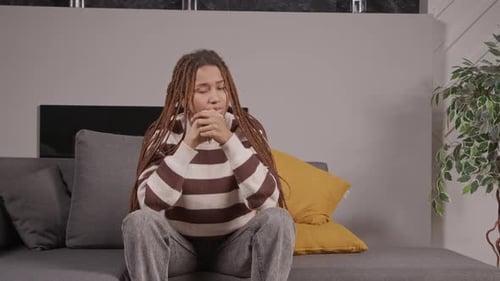 Worried Young Woman Sitting on Couch at Home