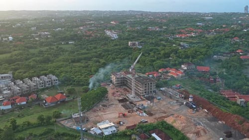 Expansive aerial footage showcasing a building under construction with a tower crane, set amidst
