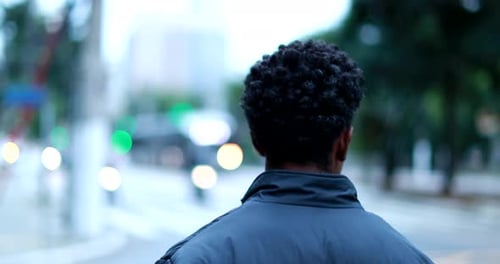 Back of black man walking in city, african american descent person walks outside casually