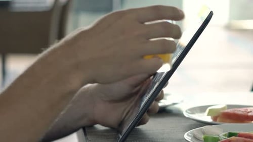 Young Man Using Tablet and Drinking Juice in Cafe 30s