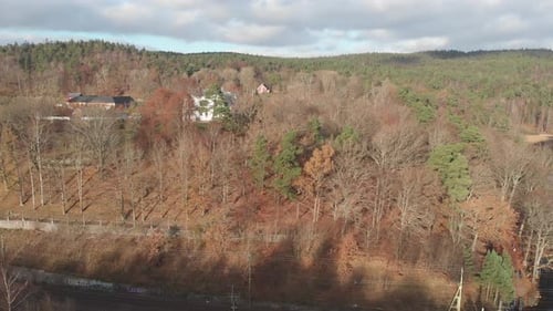 Drone flying over autumn forest scene to reveal country houses
