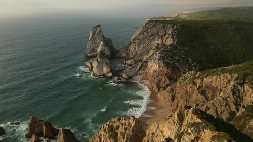 Drone Flying Above Lush Mountain With Beautiful Rock Formation in Atlantic Sea at Praia Da Ursa