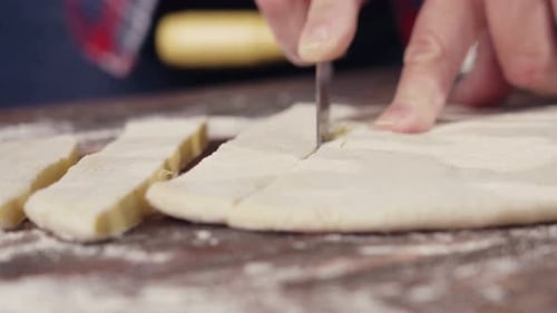 Hands Cutting Dough on a Wooden Cutting Board