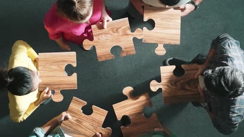 Top view of business people gathering jigsaw together at meeting. Symposium.